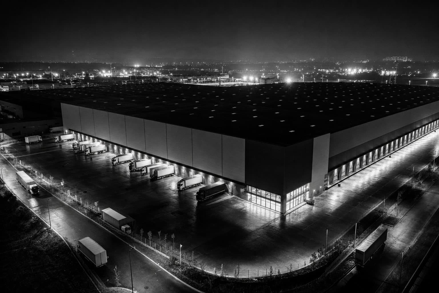Logistics warehouse at night with trucks at the docks